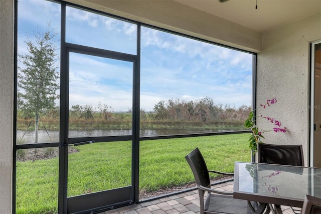 unfurnished sunroom with plenty of natural light, ceiling fan, and a water view