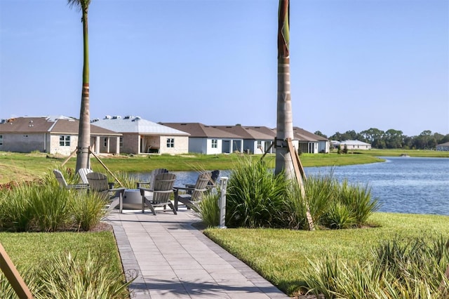 exterior space featuring a water view, a patio area, and a lawn