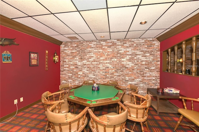 rec room featuring brick wall, crown molding, a drop ceiling, and carpet flooring