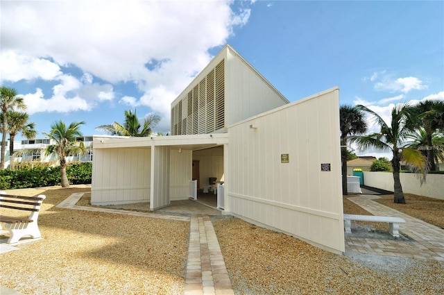 rear view of house featuring central air condition unit and a carport