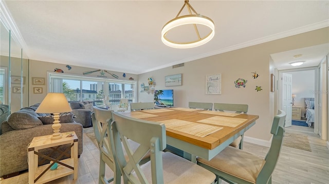 dining space with light hardwood / wood-style floors and crown molding