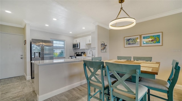 dining space with crown molding and sink