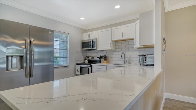 4380 Exeter Dr Unit 303, Longboat Key, FL 34228 - kitchen featuring stainless steel appliances, a sink, tasteful backsplash, white cabinets, and crown molding