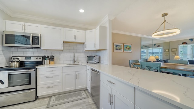 4380 Exeter Dr Unit 303, Longboat Key, FL 34228 - kitchen with appliances with stainless steel finishes, a sink, white cabinetry, crown molding, and decorative backsplash