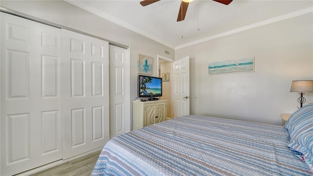 4380 Exeter Dr Unit 303, Longboat Key, FL 34228 - bedroom with light wood-style floors, ornamental molding, a closet, a ceiling fan, and a textured ceiling