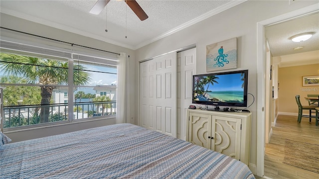 bedroom featuring crown molding, ceiling fan, a textured ceiling, light hardwood / wood-style floors, and a closet