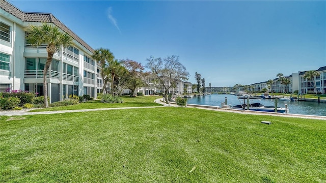 view of community featuring a dock, a water view, and a yard