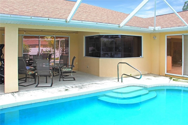 view of swimming pool with glass enclosure and a patio