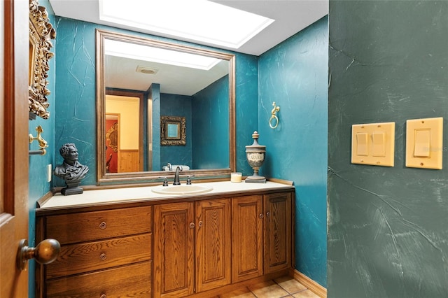 bathroom with tile patterned flooring, vanity, and a skylight