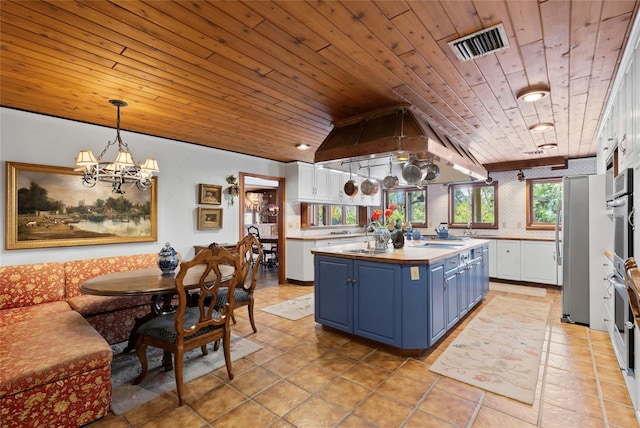 kitchen featuring blue cabinetry, a center island, white cabinets, and pendant lighting