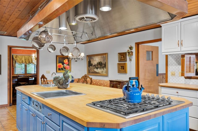 kitchen featuring a center island, white cabinets, decorative backsplash, blue cabinetry, and butcher block countertops