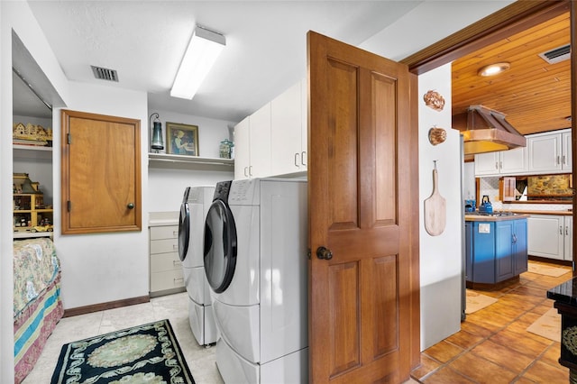 laundry area with cabinets, washing machine and dryer, and light tile patterned flooring