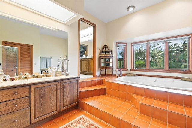 bathroom featuring tile patterned floors, vanity, and a relaxing tiled tub