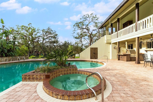 view of swimming pool featuring an in ground hot tub, a patio area, and exterior kitchen