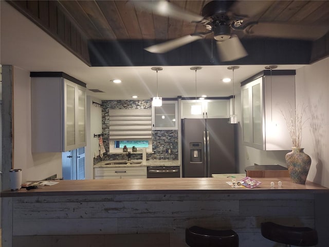 kitchen featuring decorative backsplash, pendant lighting, sink, stainless steel appliances, and kitchen peninsula