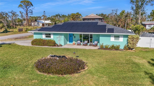 rear view of property featuring solar panels, a yard, and a patio area