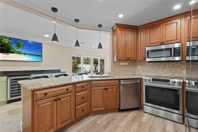 kitchen featuring sink, ornamental molding, appliances with stainless steel finishes, kitchen peninsula, and beverage cooler