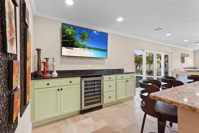 interior space featuring crown molding, beverage cooler, green cabinets, and dark stone countertops