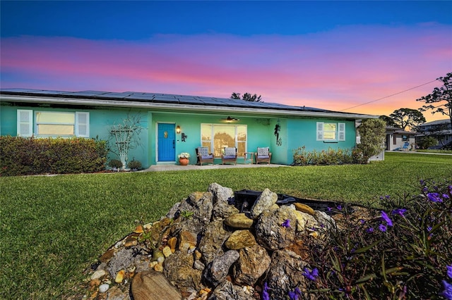 single story home featuring solar panels and a lawn