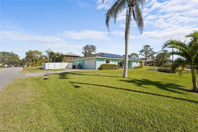 ranch-style house featuring a garage, a front yard, and solar panels