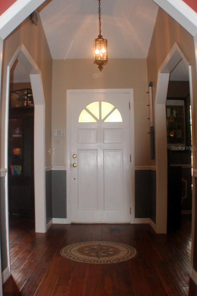 foyer with dark wood-type flooring, lofted ceiling, and a notable chandelier