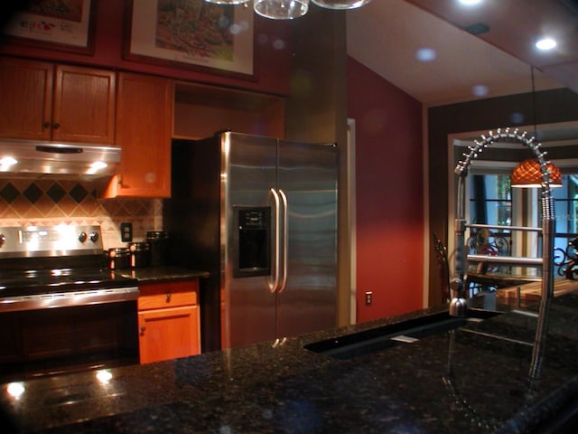 kitchen featuring pendant lighting, dark stone countertops, backsplash, and appliances with stainless steel finishes