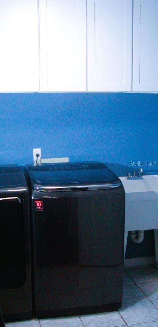 interior space featuring light tile patterned floors, cabinets, and washing machine and clothes dryer