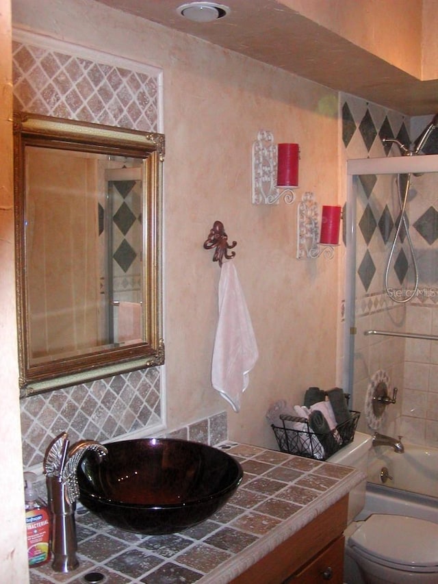 full bathroom with vanity, toilet, backsplash, and tiled shower / bath combo