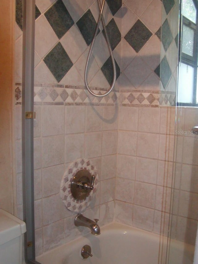 bathroom with toilet and tiled shower / bath combo