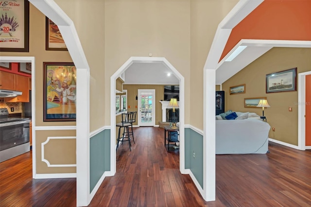 hall featuring a towering ceiling and dark wood-type flooring