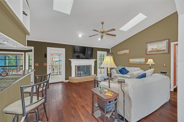 living room featuring ceiling fan, dark wood-type flooring, vaulted ceiling with skylight, and a fireplace