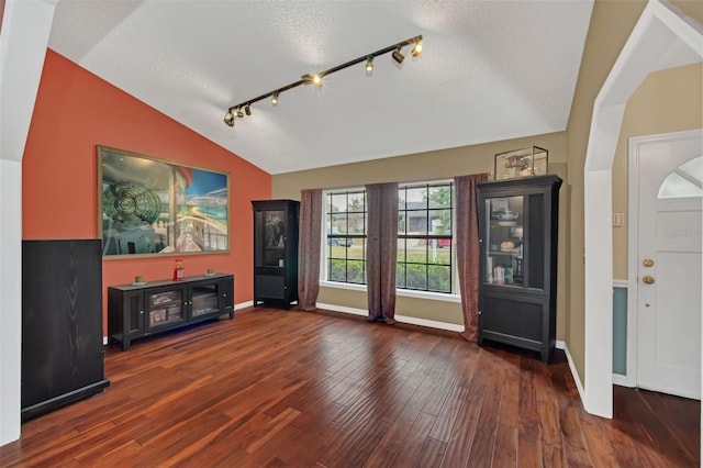 foyer entrance with dark wood-type flooring, lofted ceiling, rail lighting, and a textured ceiling