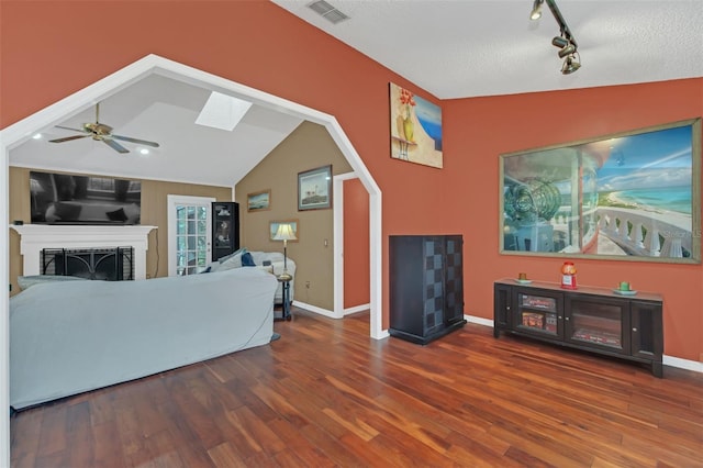 living room with wood-type flooring, vaulted ceiling with skylight, track lighting, and ceiling fan