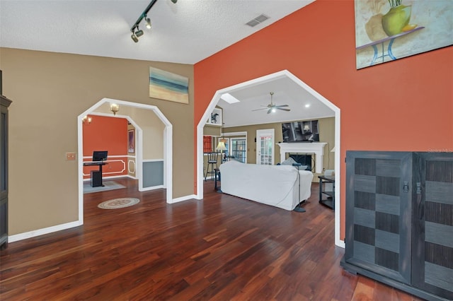 bedroom featuring vaulted ceiling, rail lighting, a textured ceiling, and dark hardwood / wood-style flooring