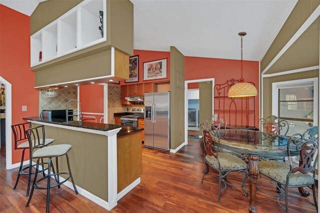 kitchen featuring dark hardwood / wood-style floors, pendant lighting, sink, kitchen peninsula, and stainless steel appliances