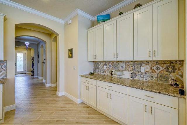 kitchen with white cabinets, light hardwood / wood-style flooring, ornamental molding, and light stone countertops