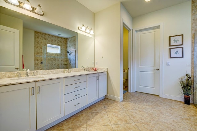 bathroom with tile patterned flooring, a tile shower, vanity, and toilet