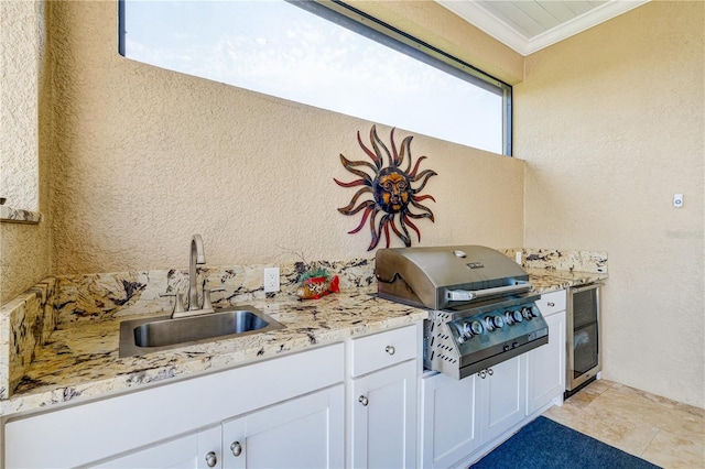 kitchen featuring ornamental molding, a healthy amount of sunlight, sink, and white cabinets