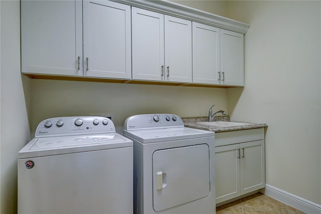 clothes washing area with washer and clothes dryer, light tile patterned floors, cabinets, and sink