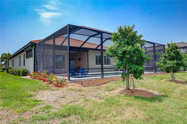 back of property with a patio, a yard, and a lanai