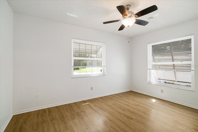 empty room with a textured ceiling, light hardwood / wood-style floors, ceiling fan, and a wealth of natural light