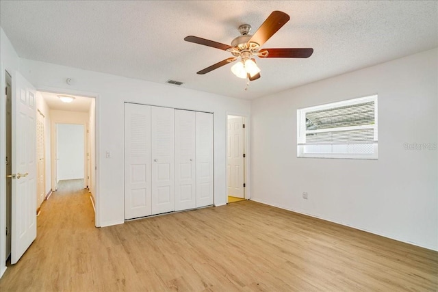 unfurnished bedroom featuring a textured ceiling, ceiling fan, light hardwood / wood-style flooring, and a closet