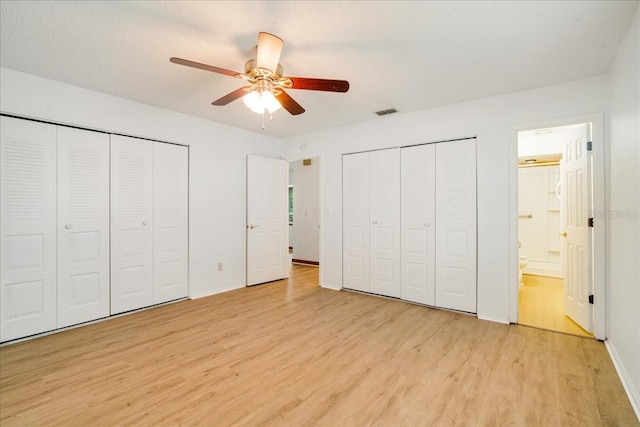 unfurnished bedroom with light hardwood / wood-style floors, ceiling fan, ensuite bath, and multiple closets