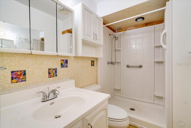 bathroom featuring vanity, toilet, backsplash, and a tile shower