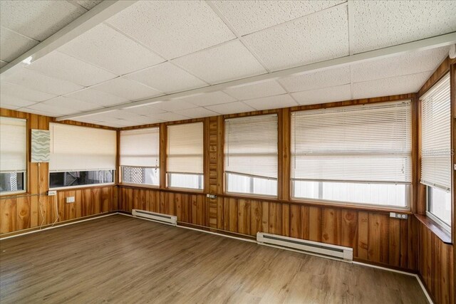 unfurnished sunroom with a drop ceiling and a baseboard heating unit