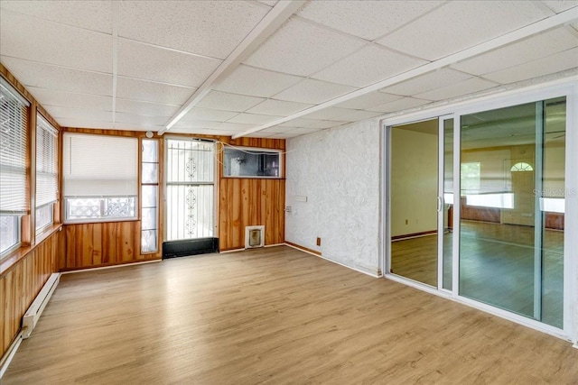 unfurnished sunroom featuring a paneled ceiling and a baseboard heating unit