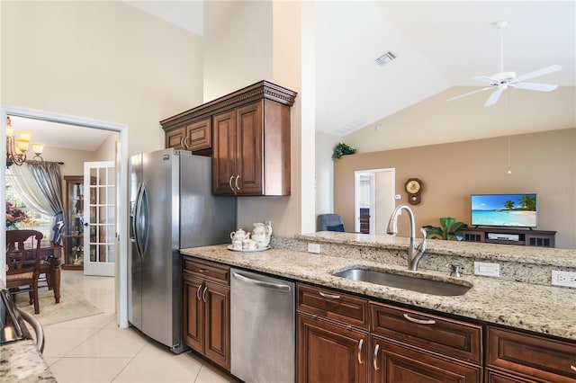 kitchen with light tile patterned floors, light stone countertops, high vaulted ceiling, stainless steel appliances, and sink