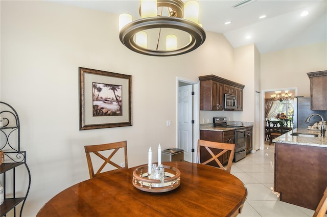 dining area with sink, a notable chandelier, high vaulted ceiling, and light tile patterned floors