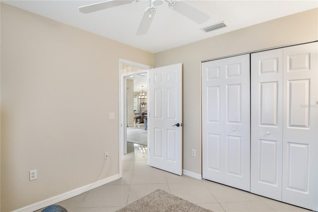 unfurnished bedroom with light tile patterned flooring, a closet, and ceiling fan