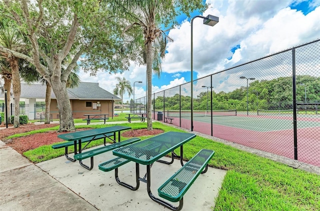 view of home's community with a lawn and tennis court